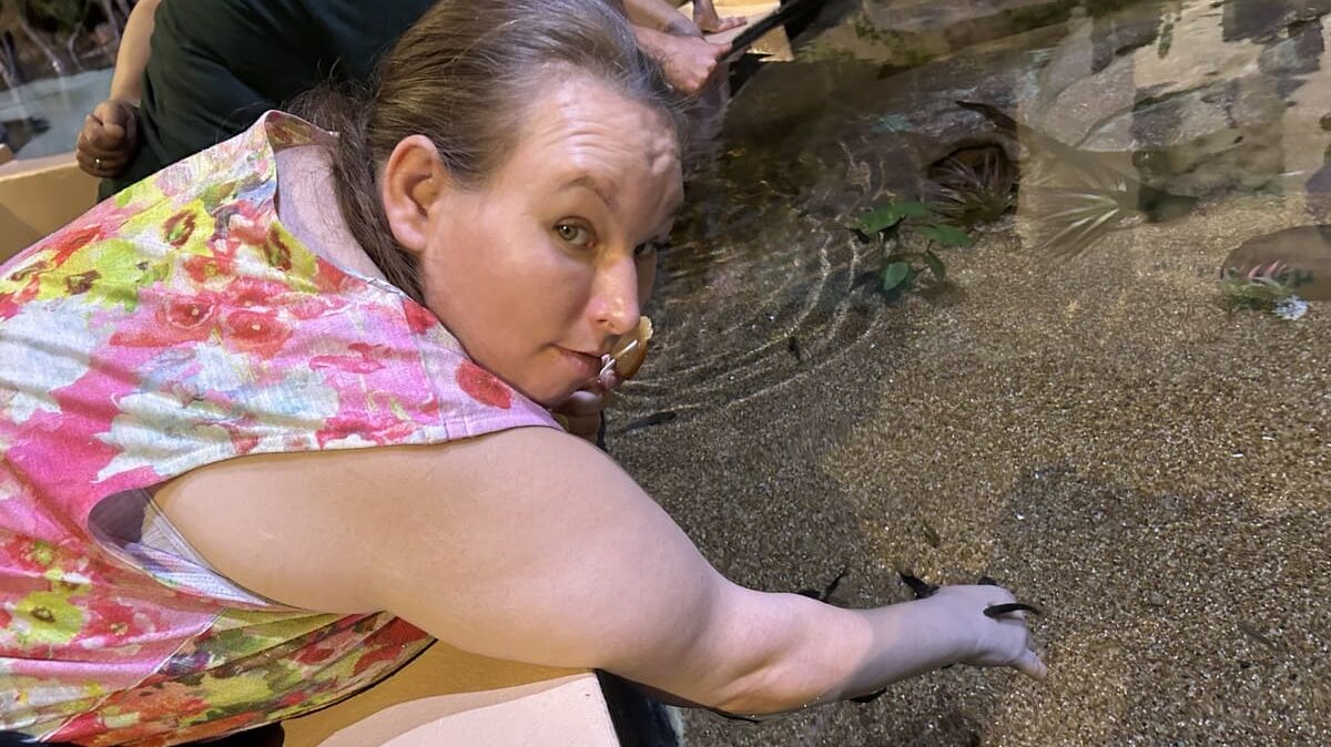 girl with hand in water touching sand