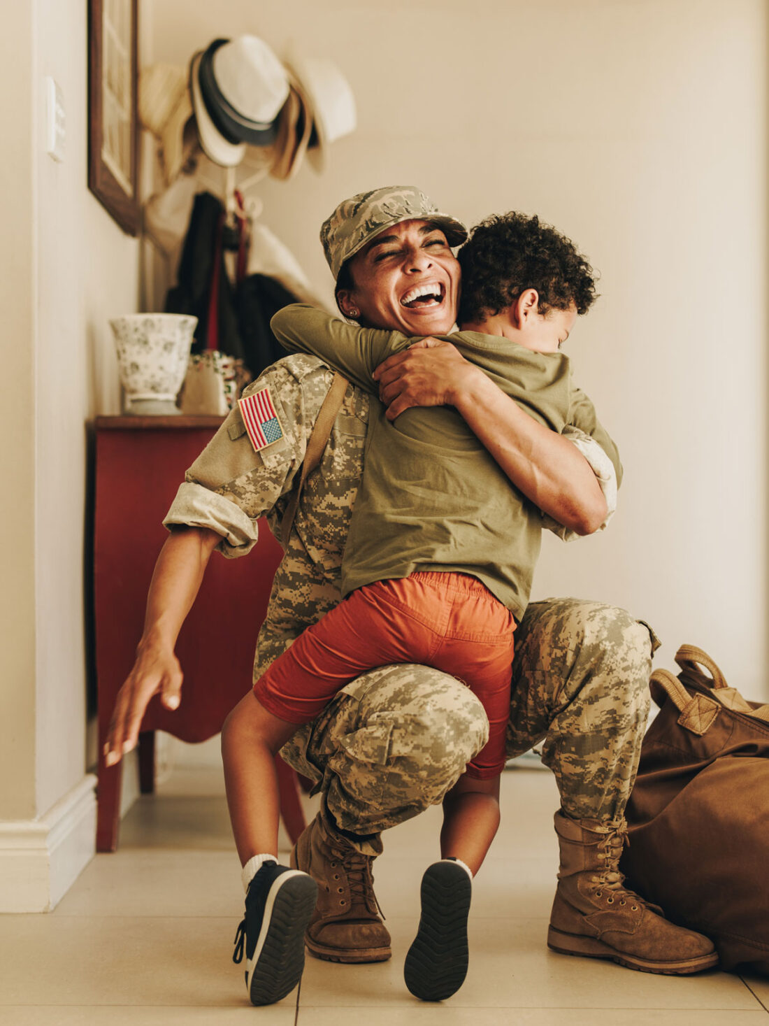 US army soldier smiling while hugging her son.