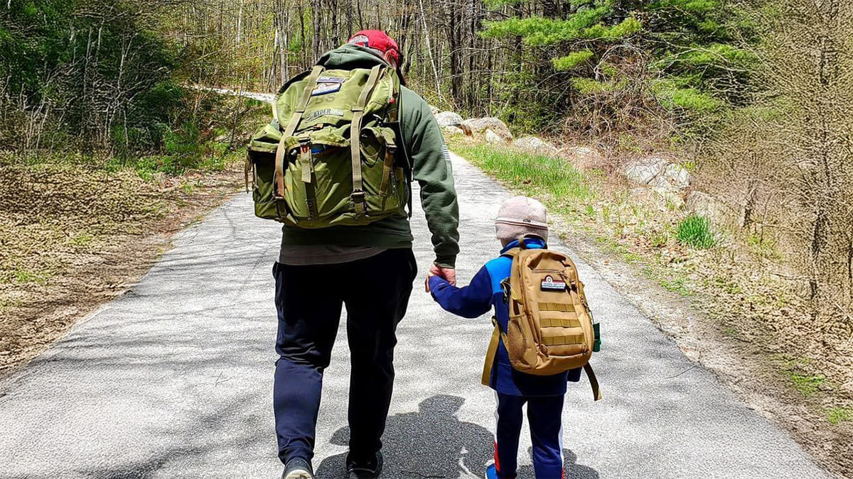 Father and son walking on a trail through the woods.